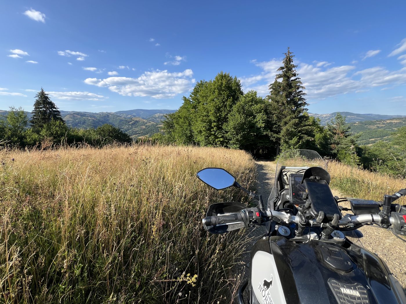 Two motorcycles beside a large wooden cross on a rocky summit