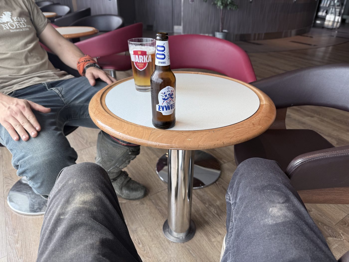 Two pairs of dirty jeans and two bottles of Polish beer on a ferry table