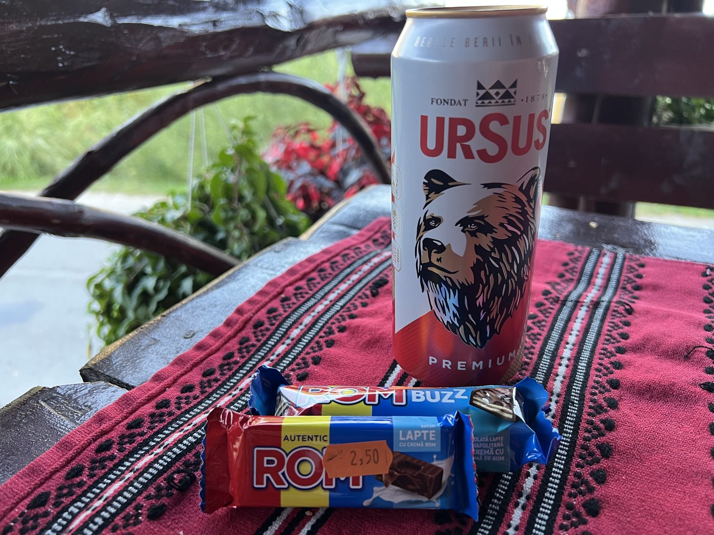 A can of Ursus beer and two ROM chocolate bars on an embroidered cloth