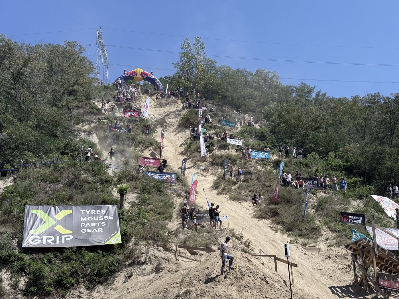 Riders on a steep sand hill climb at the Red Bull Romaniacs, crowds watching